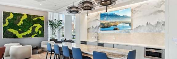 A modern dining room with a large painting on the wall and a TV above the dining table.