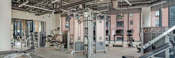 A gym with a variety of equipment including treadmills, weights, and exercise machines.