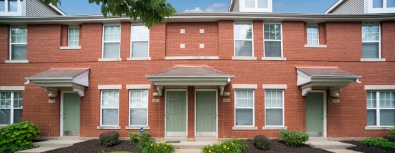 the front of a brick apartment building with steps leading up to the front door