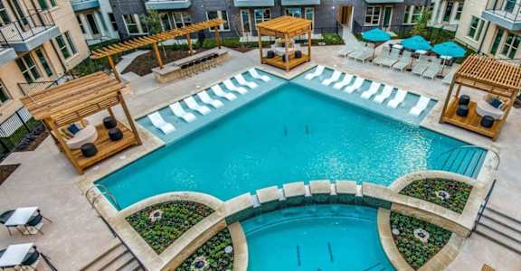 A large outdoor swimming pool surrounded by lounge chairs and umbrellas.