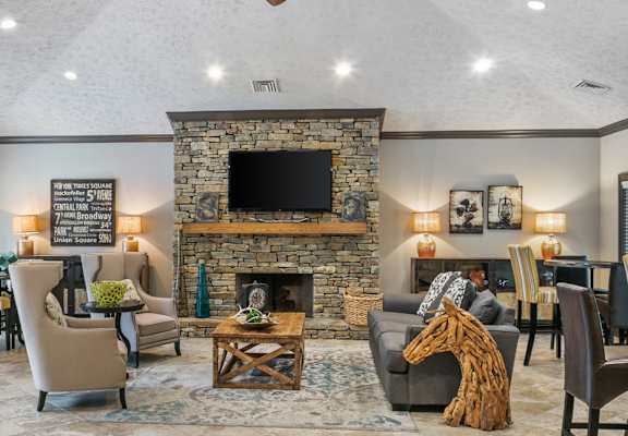 A living room with a stone fireplace and a flat screen TV mounted above it at Ridge Crossings Apartments, Hoover, AL