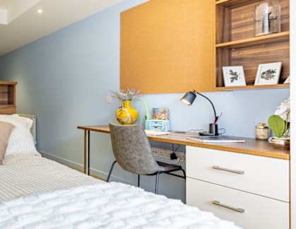 A bedroom with a bed, desk, and chair.