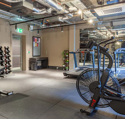 a gym with weights and cardio equipment and a tv on the wall