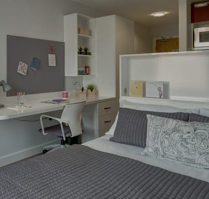 A bedroom with a bed, desk, and chair.
