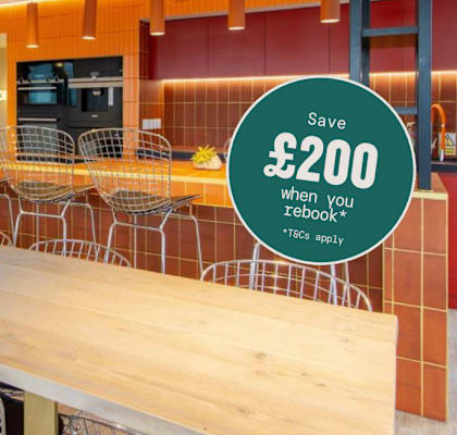A dining area with a long table and chairs, and a sign offering a £200 discount.
