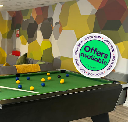 A billiard table is in the middle of a room with a colorful wallpaper.