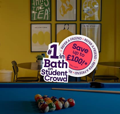 A billboard advertising a discount on baths for students is in the foreground of a room with a pool table.