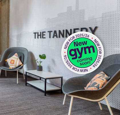 A room with a wall mural that says "The Tannery" and a sign that says "New Gym Coming Soon".