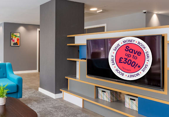 A living room with a blue couch and a television displaying a £300 saving offer.