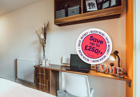 A bedroom with a bed, desk, and a sign offering a discount.