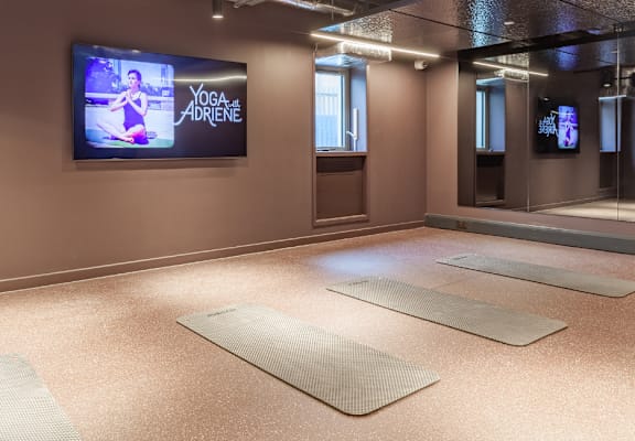 a yoga room with mats on the floor and a tv on the wall