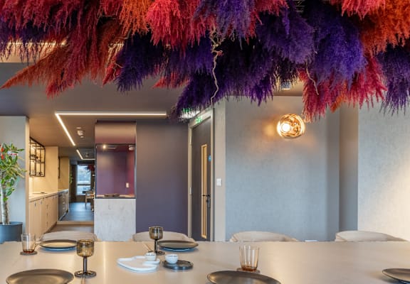 a dining room with a long table and a colorful chandelier