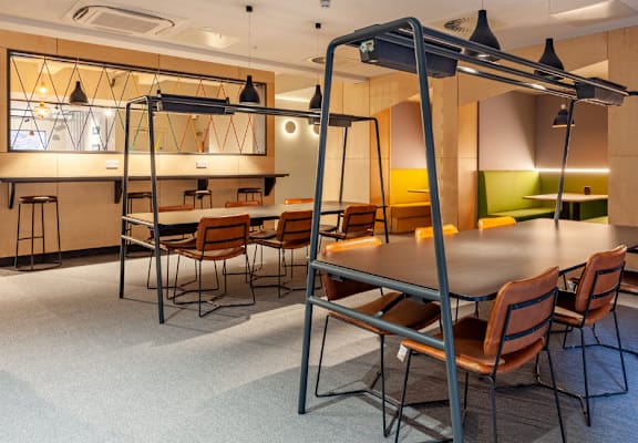 a room with a long table and chairs and a kitchen in the background