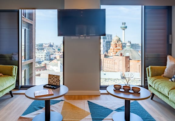 a living room with two green couches and a large window with a view of the city