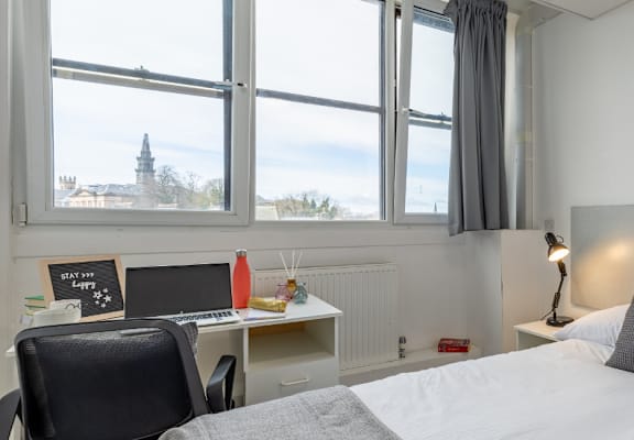 a bedroom with a bed and a desk and three windows