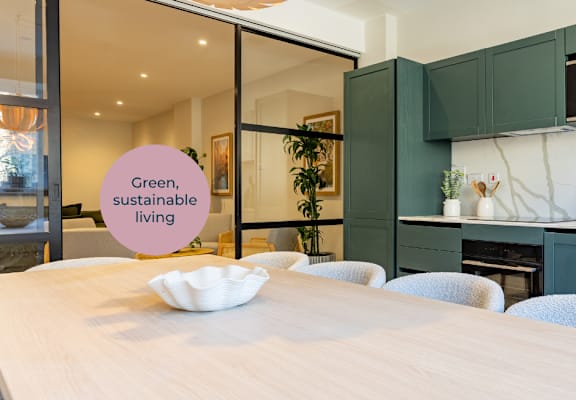 A kitchen with green cabinets and a white table.