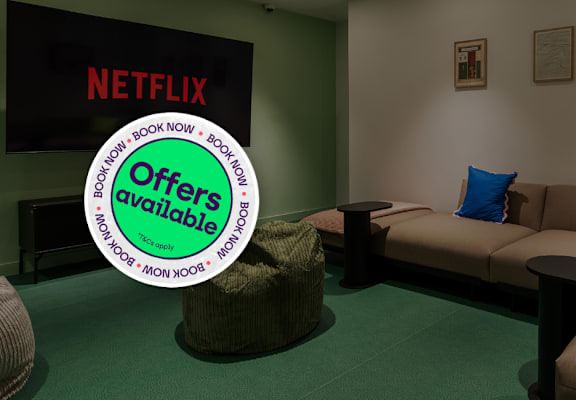 A living room with a couch and a green ottoman.
