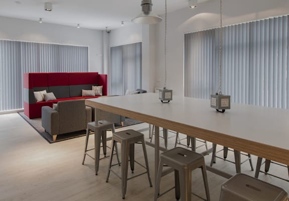 A modern living room with a red couch and a long wooden table.