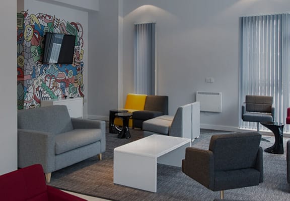 A room with a large mural on the wall and several chairs and tables.