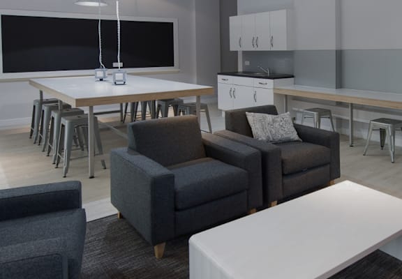 A modern living room with a grey couch, a white table, and a television.