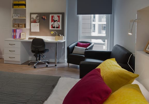 A room with a desk, chairs and a couch.
