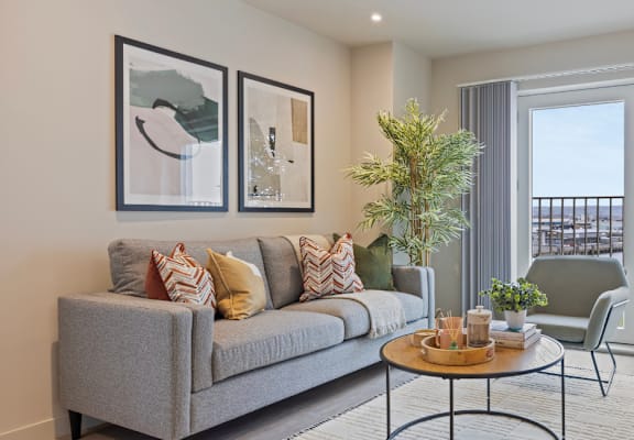A living room with a grey couch, a coffee table, and a view of a balcony.