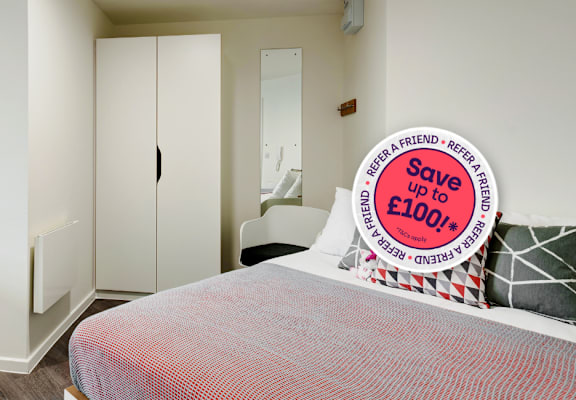 A bedroom with a bed, desk, and chair, and a sign offering a discount.