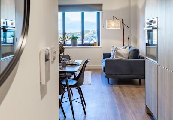 a view of a kitchen and a living room from a hallway with a dining table