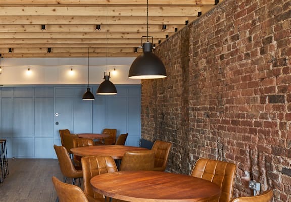 a dining room with wooden tables and chairs and a brick wall