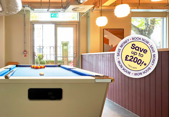 A billiard table is in a room with a sign offering a discount.