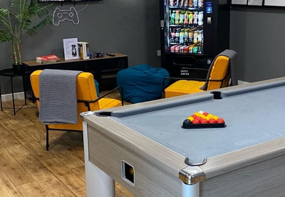 A pool table with a green cloth and a white cue ball in the middle.