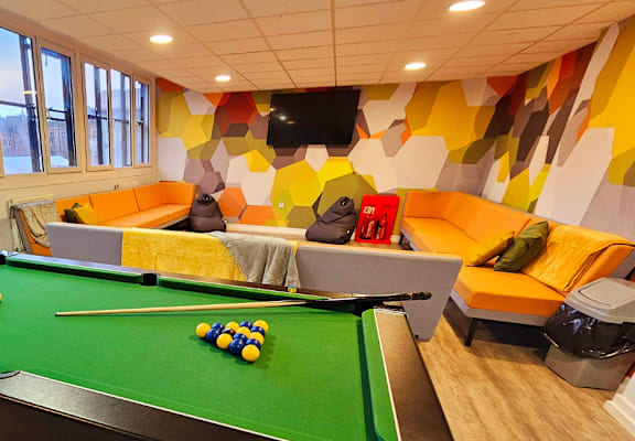 a game room with a pool table and orange couches