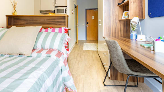 A bedroom with a bed, desk, and chair.