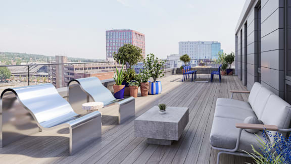 A wooden deck with chairs and tables overlooking a city.
