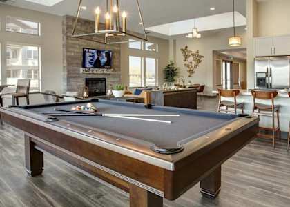A pool table is in the middle of a room with a tv and a fireplace.