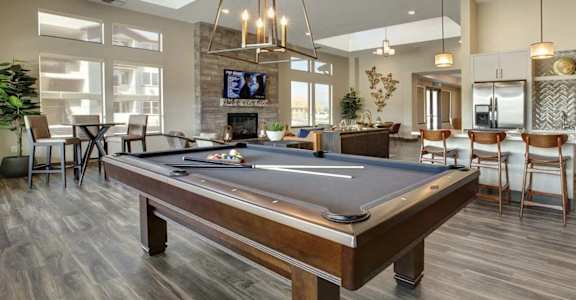 A pool table is in the middle of a room with a tv and a fireplace.