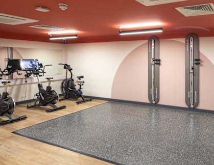 A gym with a variety of equipment including treadmills, stationary bikes, and weight machines.