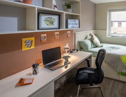 A small room with a bed, desk, and chair.