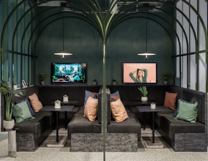 A room with a green wall and a black couch with a TV on the wall.