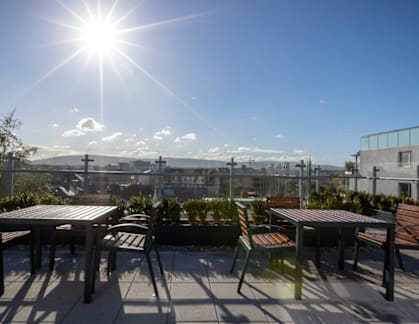A sunny day on a rooftop patio with a table and chairs.