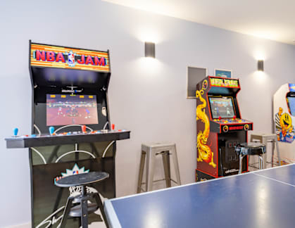 A ping pong table is in the middle of a room with arcade games.