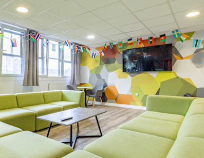 A brightly colored room with a green couch and a TV on the wall.