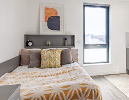 A bedroom with a bed, a television, and a window.