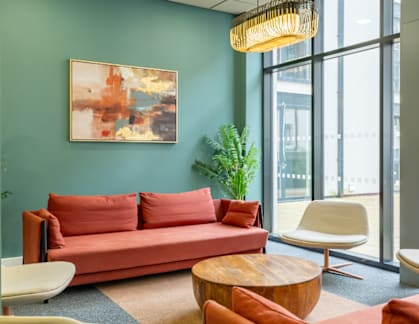 A living room with a red couch and a painting on the wall.