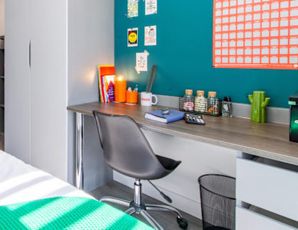 A bedroom with a bed, desk, and chair.