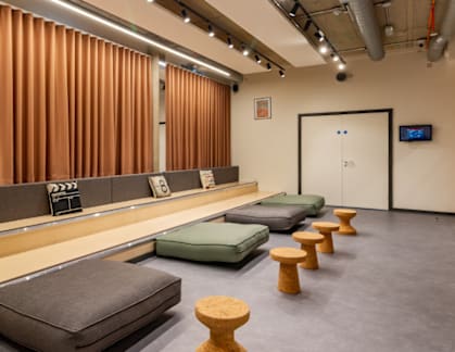 A room with a row of cushions and a row of stools.
