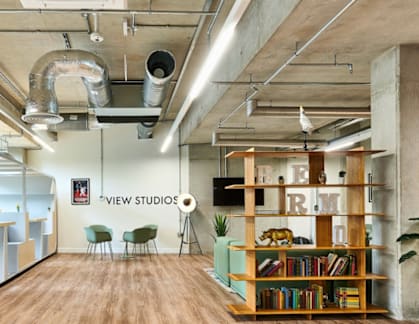 A modern office space with a wooden floor and exposed ceiling pipes.