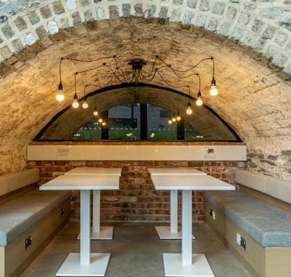 A stone archway leads to a cozy dining area with tables and chairs.