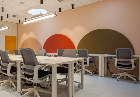 A conference room with a white table and grey chairs.