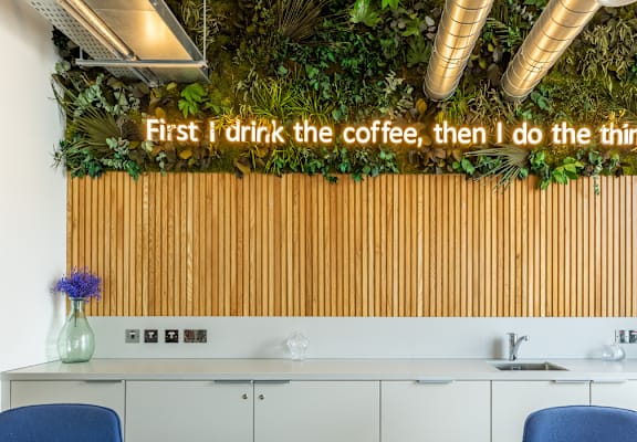A modern kitchen with a green wall and a quote on it.